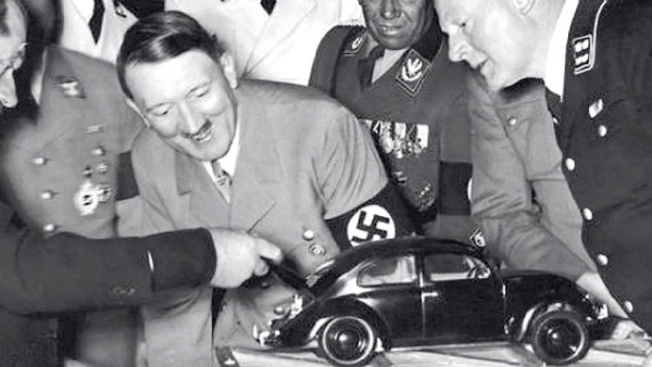 تصویری تاریخی از هیتلر که تحت‌تأثیر ماکت فولکس‌واگن قرار گرفته است. فردیناند پورشه (سمت چپ) برای او توضیح می‌دهد.